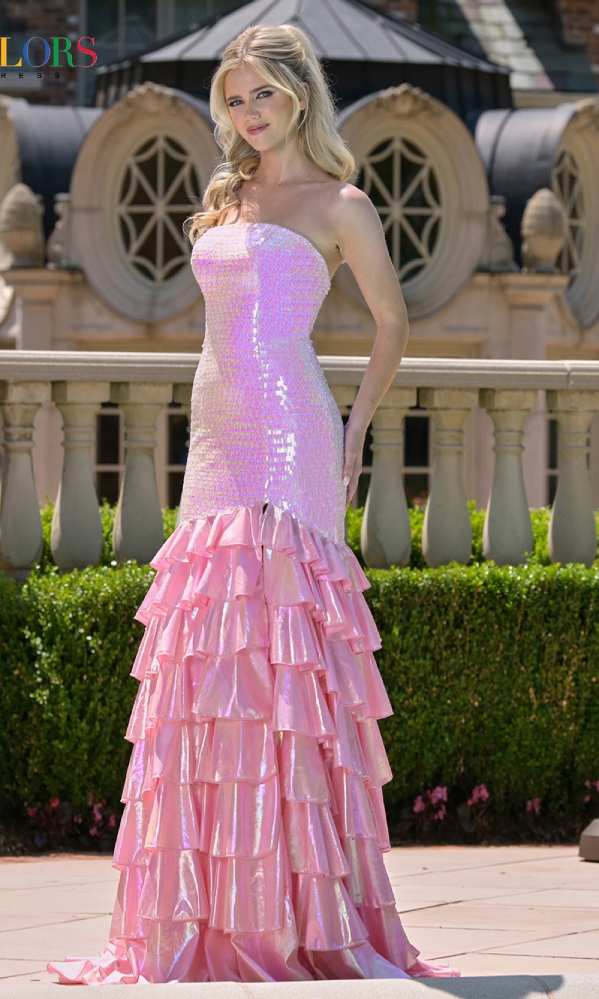 Woman wearing a pink mermaid-style dress with ruffled layers in an outdoor setting.